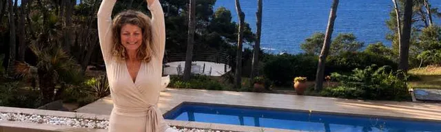 Gabrielle en posture de l’arbre sur un tapis rose, devant une piscine et la mer