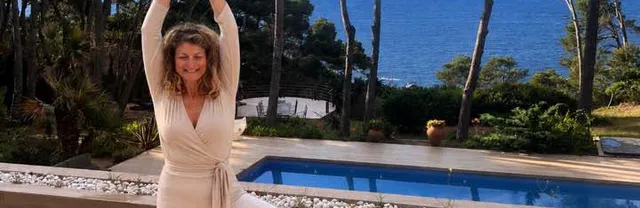 Gabrielle en posture de l’arbre sur un tapis rose, devant une piscine et la mer