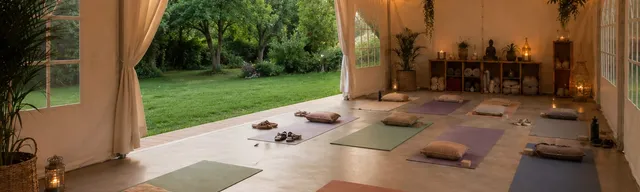 Studio de yoga ouvert sur un jardin, avec tapis, coussins et guirlandes lumineuses